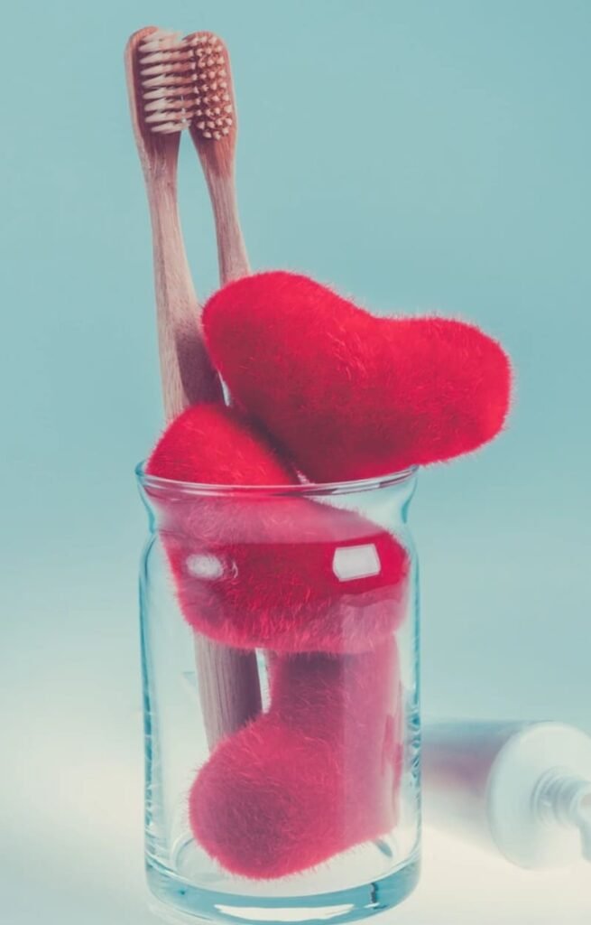 cepillos de dientes en vaso de cristal con corazones de peluche rojos